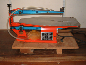 This is a used Hegner Multicut Scroll Saw mounted on a board which can be held firmly in a vice